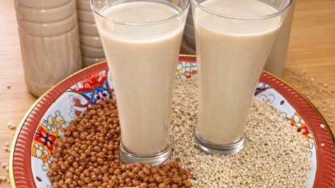 glasses-of-homemade-kunu-drink-sitting-on-millets-sorghum-and-tigenut-grains-ready-to-enjoy-and-some-bottles-containing-kunu-drink-all-sitting-on-a-dinner-table